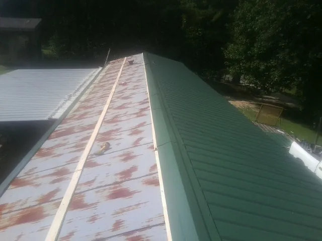 Old rusted panels beside newly installed green metal roofing — Wind Damage Roof Repair by Roofing Brothers in Larkspur