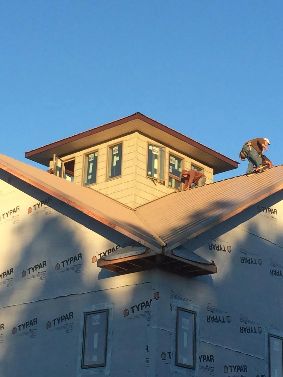 Roofers working around a rooftop cupola on a new metal roof at sunset — Roof Waterproofing in Larkspur by Roofing Brothers